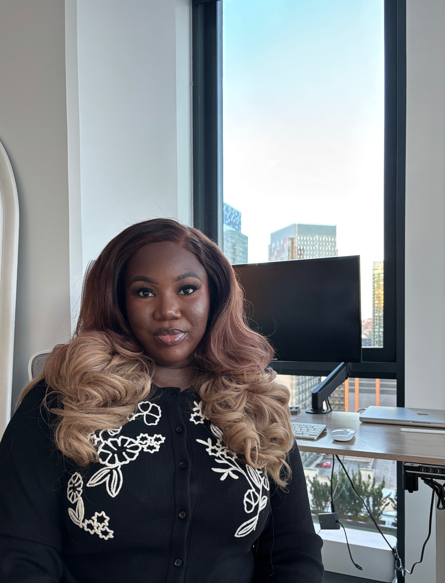 Oluseun Adesanya at her desk by a window overlooking the city